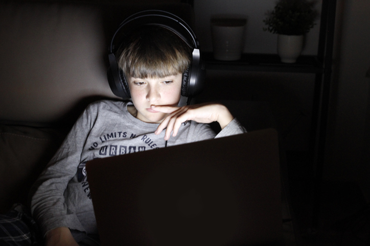 Boy Using Laptop On Sofa At Night